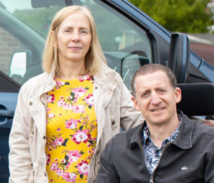 Woman in wheelchair and man next to car ramp