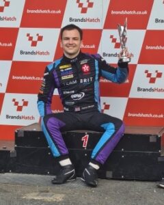 Team BRIT driver Aaron Morgan in first place holding trophy