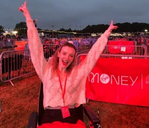 Woman outdoors, cheering in her wheelchair with hands above her head