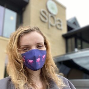 Spa Kate Kate in front of the spa wearing a flamingo face mask