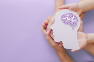 Adult and child hands holding encephalography brain paper cutout to talk about mental health