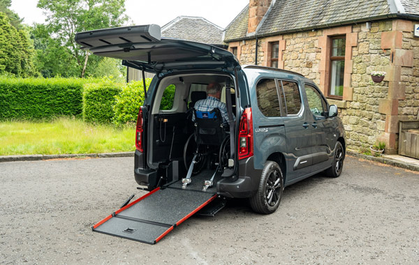 Back three quarters of Citroen Lunar with tailgate open, ramp down and wheelchair user secured inside.