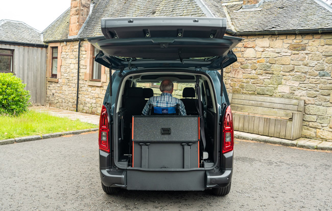 Back of Citroen Lunar with tailgate open, ramp up and wheelchair user secured inside.