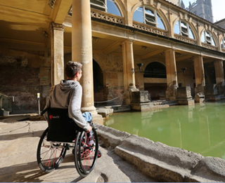 Wheelchair user inside the Roman Baths in Bath.
