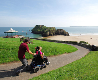 Wheelchair user and companion strolling along the Pembrokeshire Coast in Wales