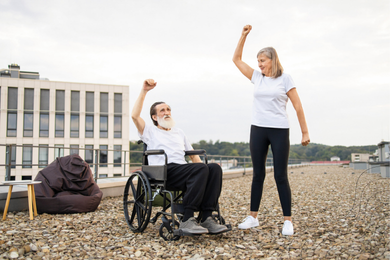 wheelchair user doing chair yoga with an able bodied woman on top of a rooftop