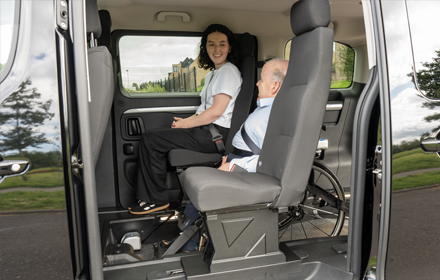 Side door of Venture is open showing the wheelchair user in their travelling position beside a woman in the passenger seat.