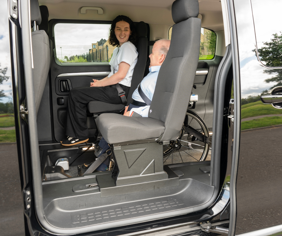 Side door of Venture is open showing the wheelchair user in their travelling position beside a woman in the passenger seat.
