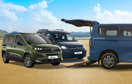 Three wheelchair-accessible vehicles parked on a sandy surface under a bright blue sky with scattered clouds. On the left is a green Peugeot Horizon WAV, in the centre a dark grey Volkswagen Vista WAV and on the right a blue Ford Independence WAV with its tailgate open and a wheelchair ramp extended to the ground.