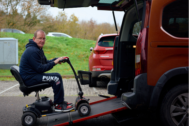 Tony driving his mobility scooter up the ramp of his wheelchair access car.