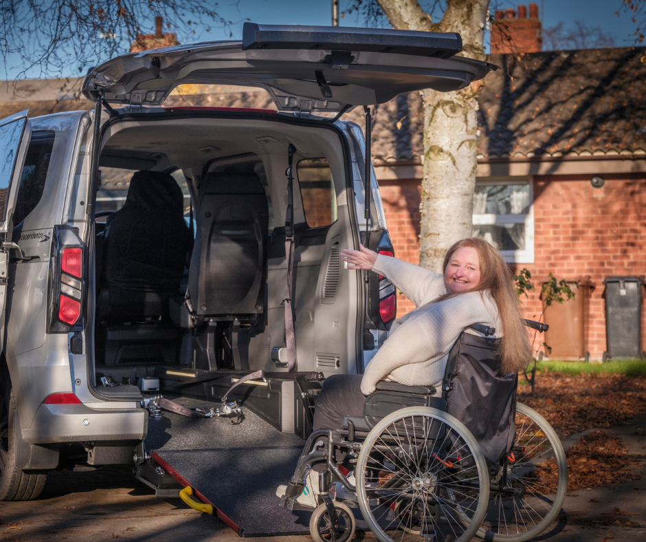 Wheelchair user using a rear ramp to access a wheelchair accessible vehicle parked on a residential street.