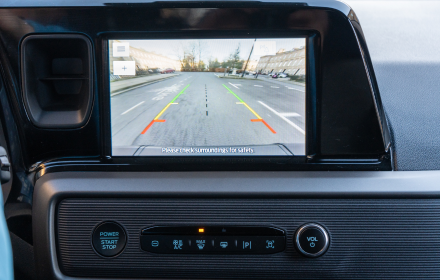 Vehicle rear view parking camera display showing coloured parking guide lines on the infotainment screen.