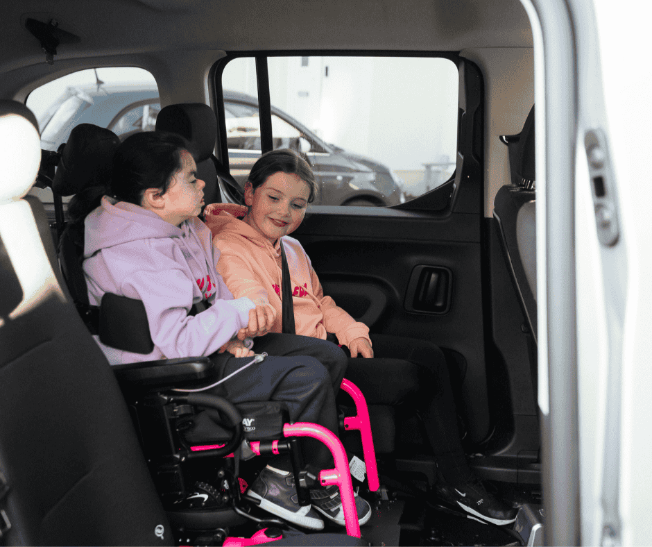 Two children, one a wheelchair user, travelling safely in row two of a wheelchair accessible vehicle.