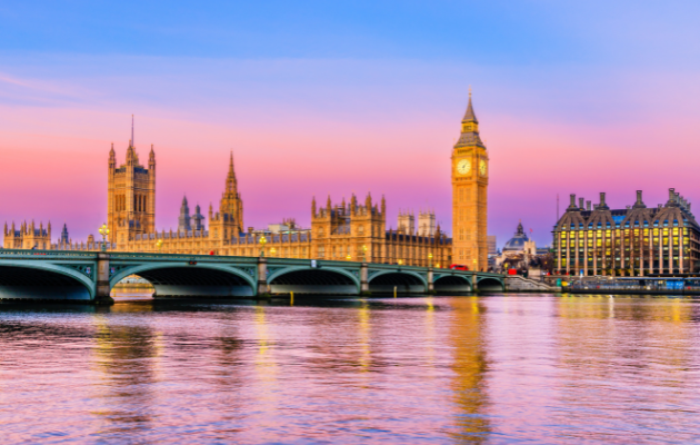 London skyline at sunset featuring Big Ben, Westminster Bridge, and the River Thames reflecting colourful skies.
